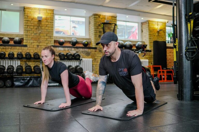 Personal trainer guiding client through injury rehab stretch in London gym