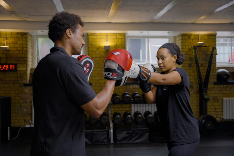 Ladies boxing with trainer using pads – personal training session for strength, conditioning and confidence.