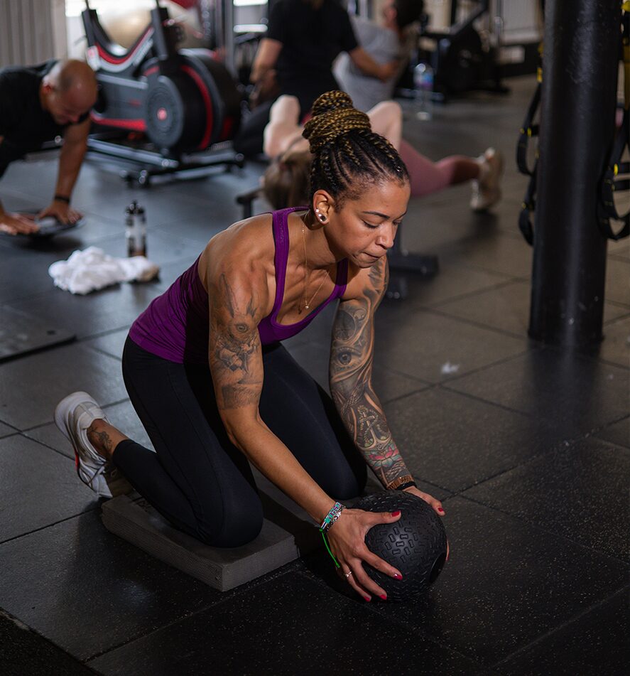 Client performing medicine ball exercise during personal training session – functional strength and core training for all fitness levels.