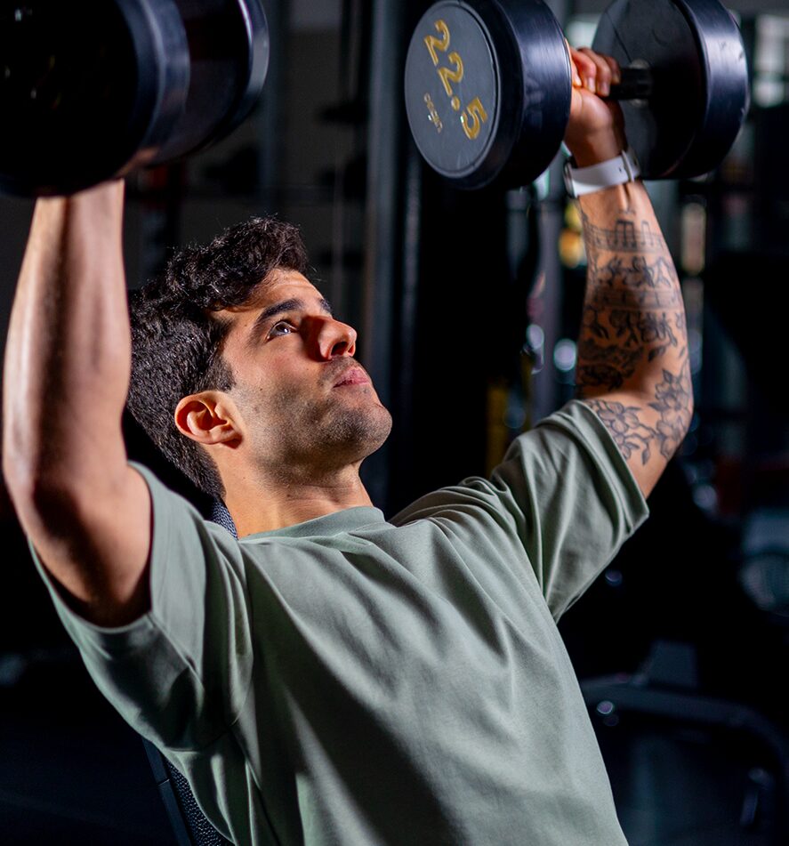 Client performing dumbbell overhead press exercise – personal training session for shoulder and upper body strength
