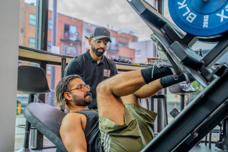 Personal trainer correcting technique during a one to one coaching session